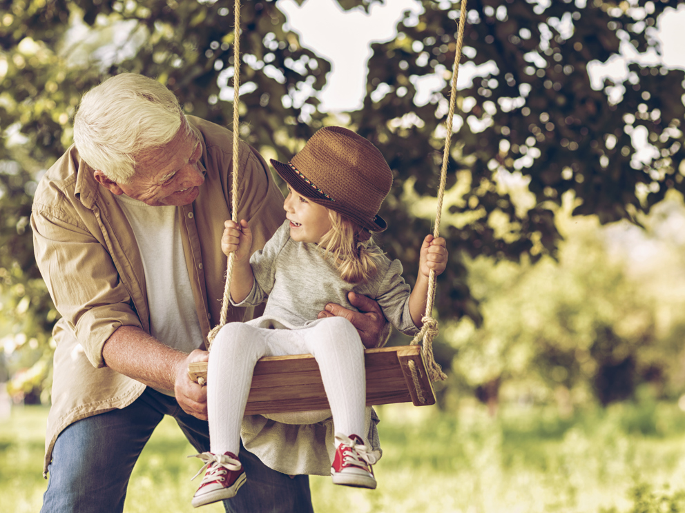 Nonno che spinge la nipote su un'altalena all'aperto 
